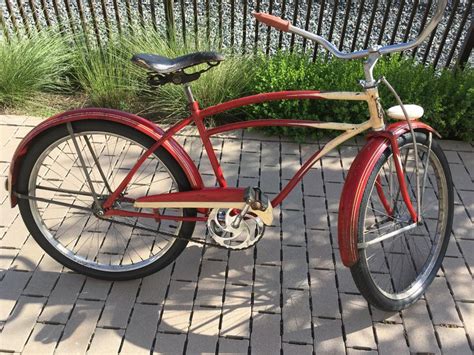 A Red Bicycle Parked On Top Of A Brick Sidewalk Next To A Fence And Grass