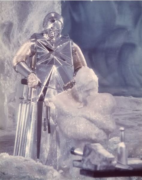 A Man Dressed In Silver Standing Next To An Ice Sculpture With Snow On