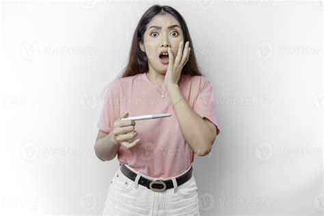 Unhappy woman wearing pink t-shirt looking at pregnancy test alone