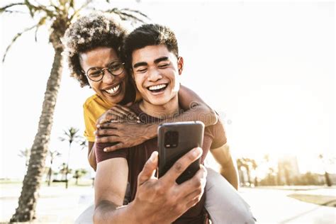 Happy Multiracial Couple Using Smart Mobile Phone Device Outside