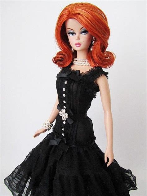 A Doll With Red Hair Wearing A Black Dress And Pearls On It S Head