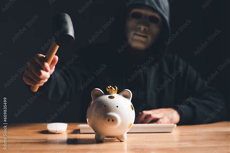 Black hat hacker in mask and hoodie trying to destroy financial piggy ...