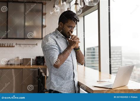 Pensive African Guy Looks At Laptop Pondering Over Problem Solution