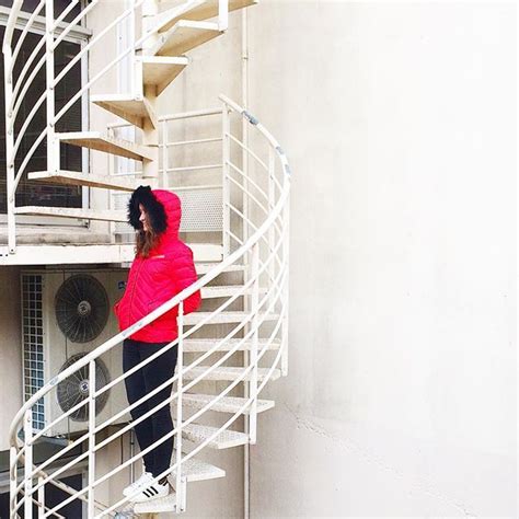 A Woman In A Red Jacket Is Standing At The Bottom Of A White Spiral