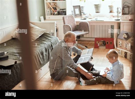 Mature Man Looking Photo Book And His Grandson Using Digital Tablet Stock Photo Alamy