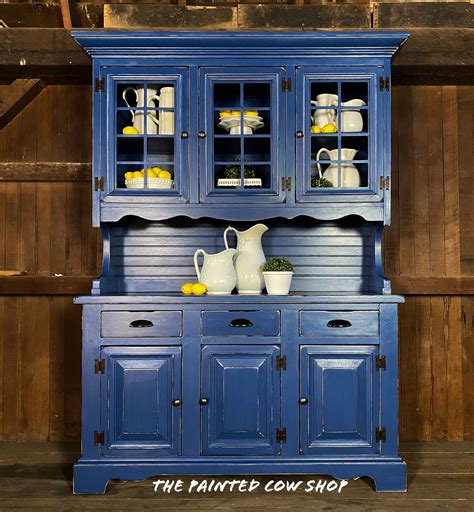 A Blue China Cabinet With Glass Doors And Yellow Dishes On It S Top Shelf