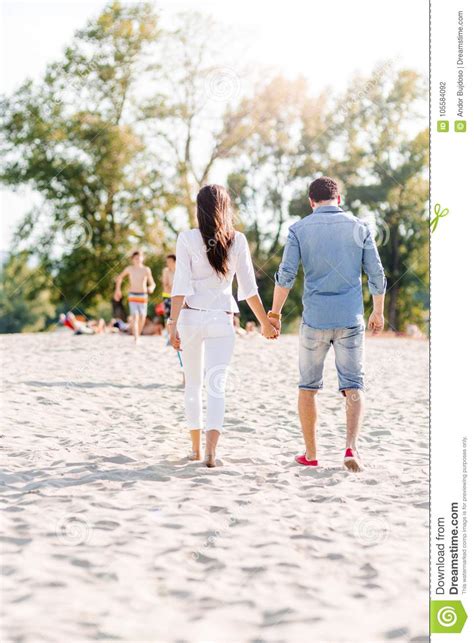 Junte Llevar A Cabo Las Manos Y Caminar En Una Playa Foto De Archivo