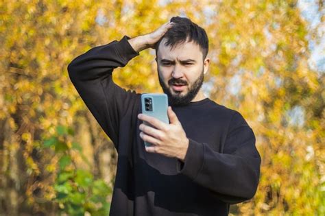 El hombre con barba mira su teléfono y está terriblemente sorprendido