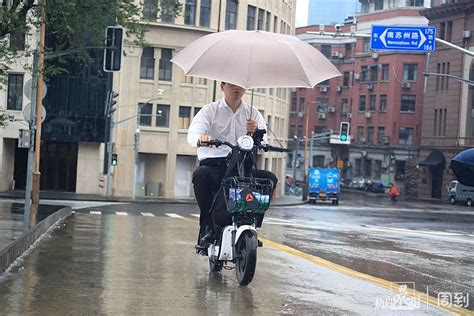 年轻女士雨中撑伞骑车摔倒，切记，撑伞骑车很危险 晨镜头 周到上海