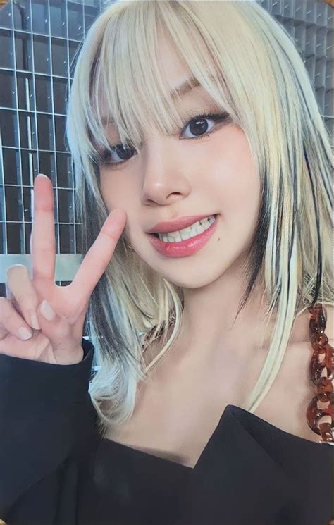 A Woman With Blonde Hair And Bangs Making The Peace Sign In Front Of