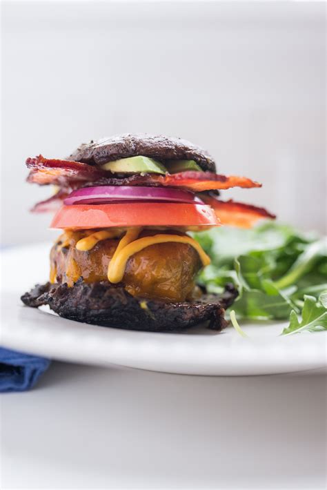 A Hamburger With Lettuce Tomato Onion And Cheese On A White Plate