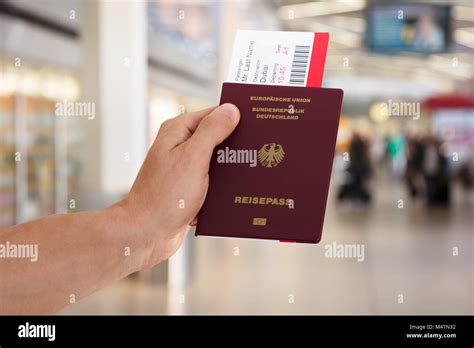 Close Up Of Hand Holding Passport And Boarding Pass In Airport Stock