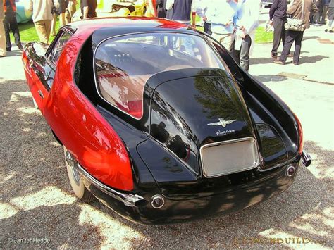 A Black And Red Sports Car Parked On The Side Of A Road With People