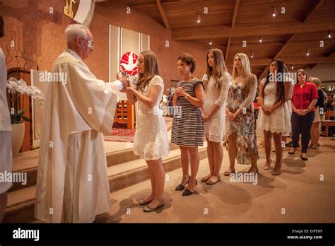 A Priest Anoints A Line Of Teen Girls During Confirmation Ceremonies At