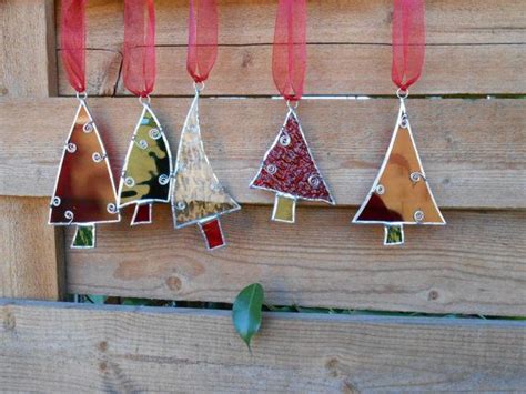 Four Stained Glass Christmas Trees Hanging From A Wooden Fence With Red Ribbon Around Them And