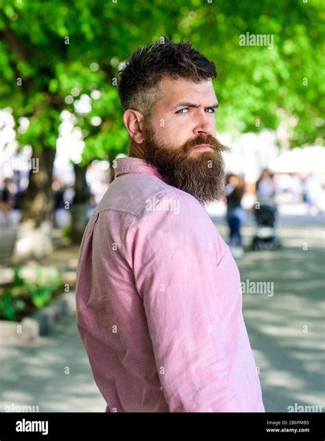 Man With Beard And Mustache On Strict Face Looks Back While Walks In Park Barber And Hairstyle