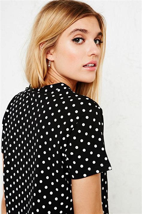 A Woman With Blonde Hair Wearing A Black And White Polka Dot Blouse