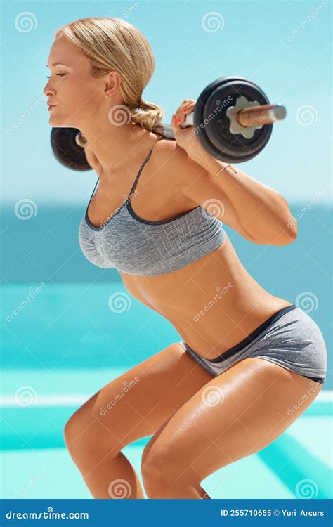 Fit And Focused An Attractive Young Woman Doing Squats With A Barbell Outside Stock Image