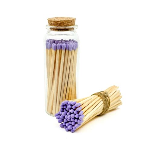 Several Matches Are In A Glass Jar Next To Some Purple And White Matchesticks