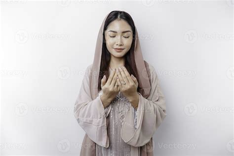 Religious Beautiful Asian Muslim Girl Wearing A Headscarf Praying To God Isolated By White