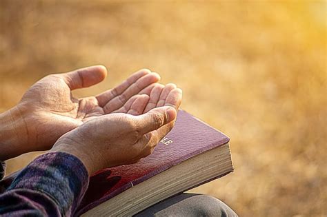 Las Manos Del Hombre Orando A Dios Con La Biblia Crean En La Bondad