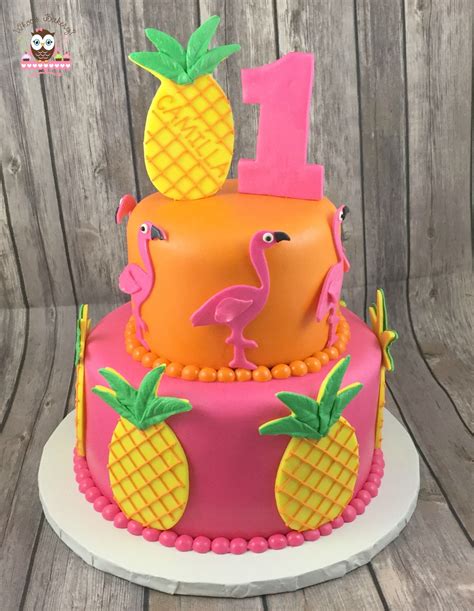 A Birthday Cake With Pineapples And Flamingos On The Top Is Decorated