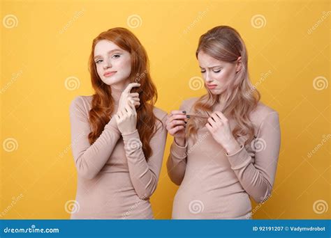 Dame Rousse Gaie Touchant Ses Cheveux Près De La Femme Blonde Triste Image stock Image du