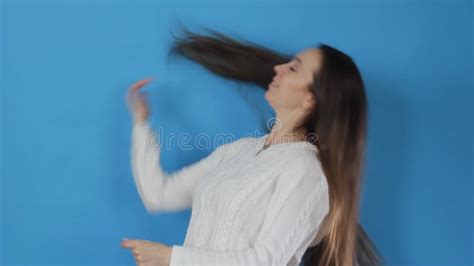 A Brunette Girl With Long Hair In A White Blouse Stylishly Dances On A Blue Background Stock