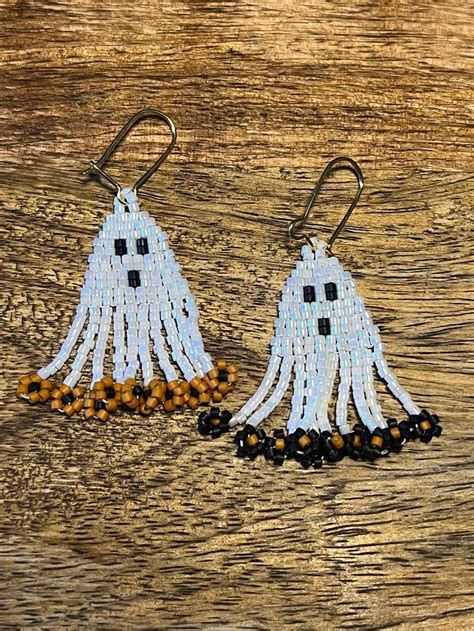 Two White Tasseled Earrings With Black Beads On Wooden Table Next To