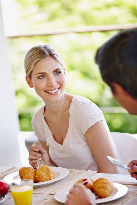 Bonding Over Breakfast A Happy Young Couple Eating Breakfast Together On The Patio At Home