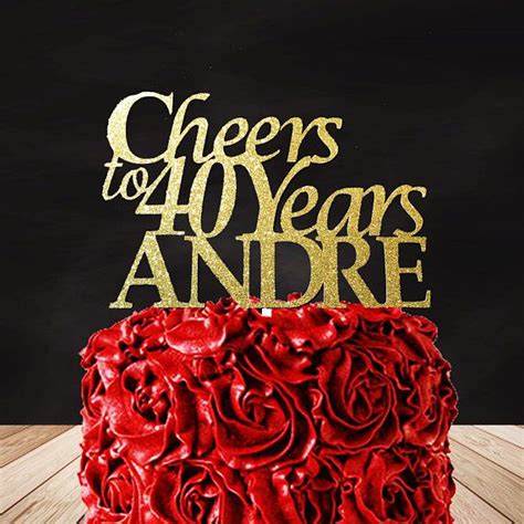 There Is A Red Cake With Gold Letters On Top And Roses In The Middle