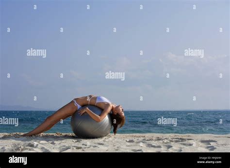 woman in bikini lying on giant ball on beach Stock Photo - Alamy