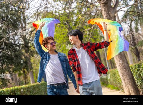 Happy Multiracial Gay Couple Walking Holding Hands And Waving Lgbt