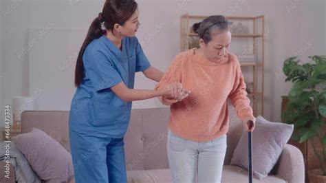 A Young Asian Female Caregiver Is Assisting An Elderly Asian Woman