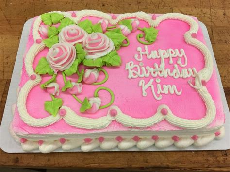 A Pink Birthday Cake With White Frosting And Flowers