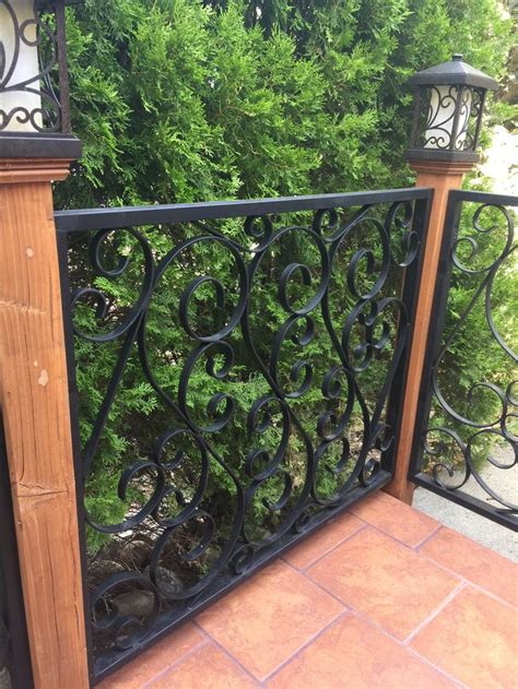 An Iron Fence With Wooden Posts And Decorative Designs On The Top Next