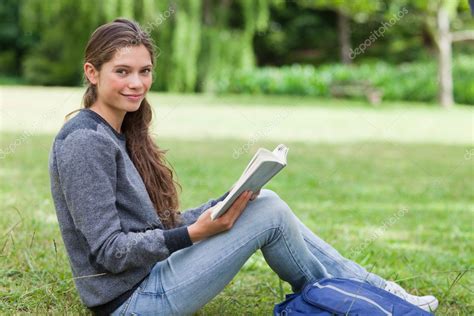 Jeune Fille Souriante Tenant Un Livre Sur Ses Genoux En Position Assise