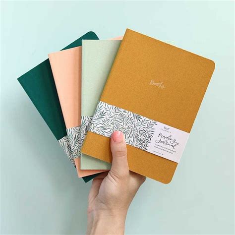 A Hand Holding Four Different Colored Notebooks