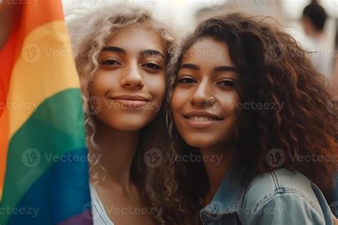 Portrait Of Happy Lesbian Couple Smiling Holding Rainbow Flags On Pride