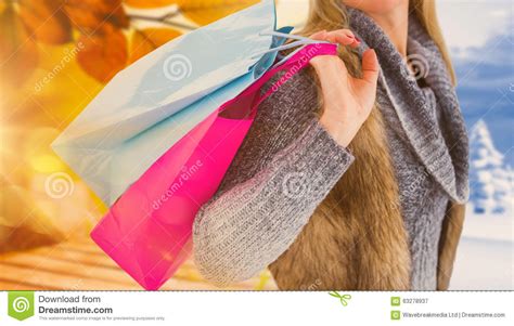 Composite Image Of Blonde In Winter Clothes Holding Shopping Bags Stock