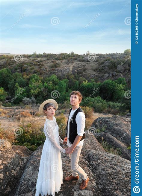 Recienes Casados Felices Que Se Colocan En Roca Foto De Archivo