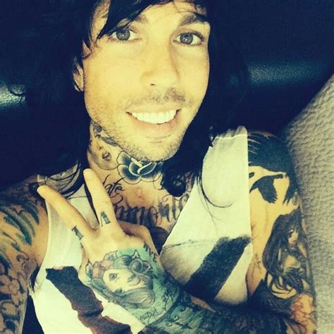 A Man With Long Hair And Tattoos On His Arm Holding Up The Peace Sign