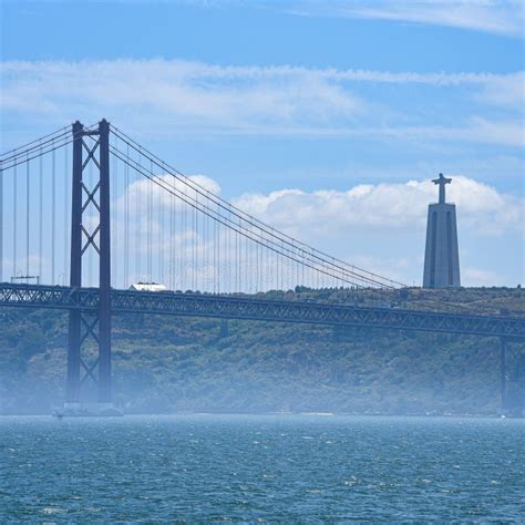 Cristo Rei Monument And The 25th Of April Bridge Over The Tagus River