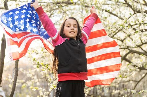 Adorável menina feliz sorrindo e acenando a bandeira americana feriado