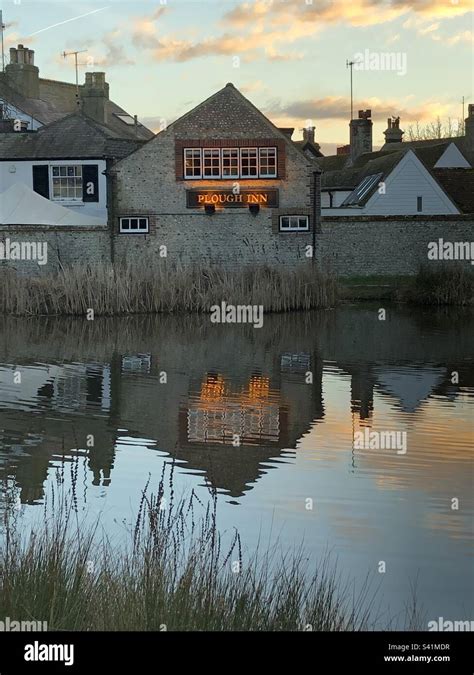 The Plough Inn Pub And Other Old Stone Buildings With Reflections In A