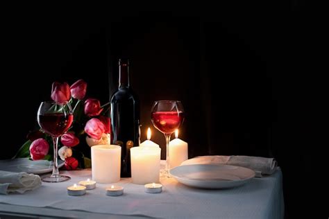 Cena romántica a la luz de las velas con vino velas y ramo de