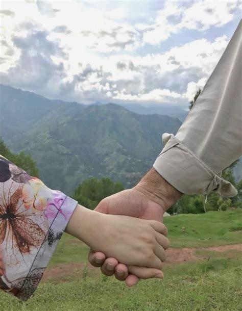 Two People Holding Hands With Mountains In The Background