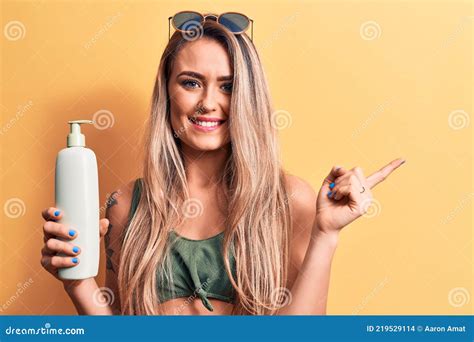 Joven Hermosa Rubia Con Bikini Y Gafas De Sol Sosteniendo Botella De Crema Protector Solar