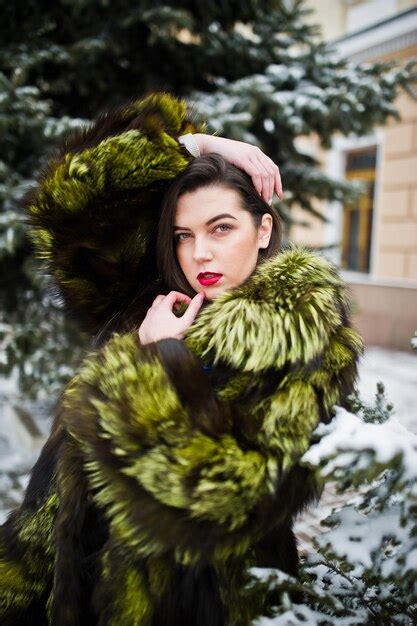 Premium Photo Brunette Girl In Green Fur Coat At Winter Day Against Snowy Pine Tree