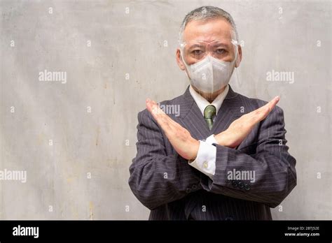 Mature Japanese Businessman With Mask And Face Shield Showing Stop
